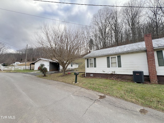 view of side of home featuring central air condition unit, a garage, an outdoor structure, and a lawn