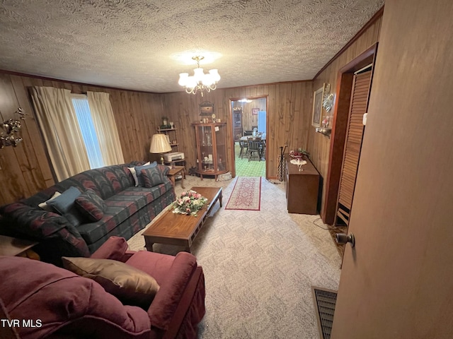 carpeted living room with wood walls, a textured ceiling, and an inviting chandelier