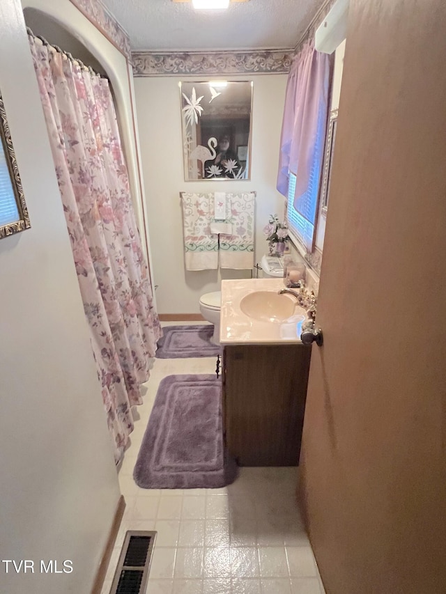 bathroom with vanity, toilet, a textured ceiling, and walk in shower