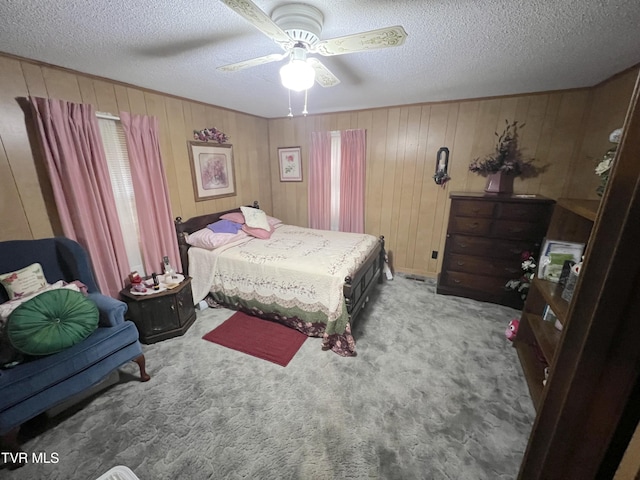 bedroom featuring ceiling fan, wooden walls, carpet floors, and a textured ceiling