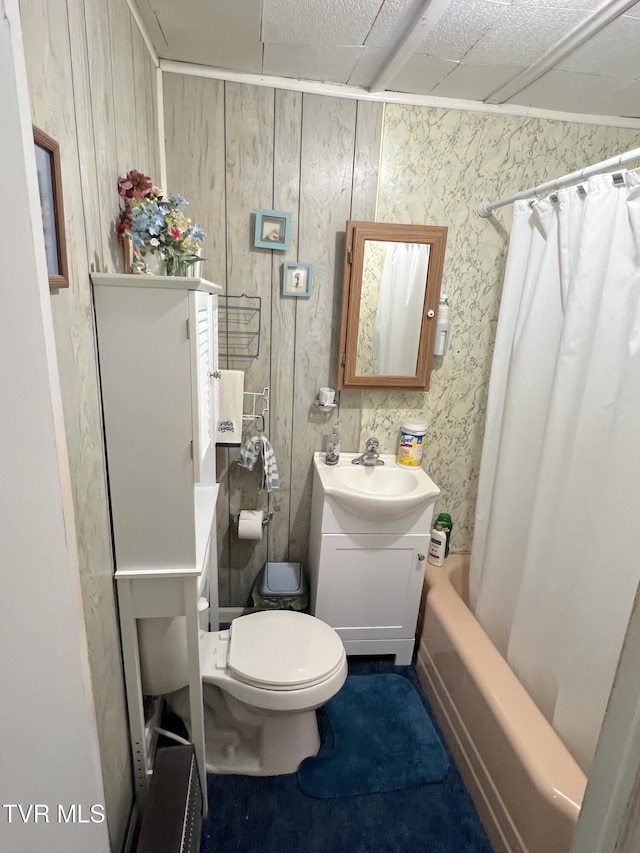 full bathroom with wood walls, vanity, shower / bath combo, and toilet