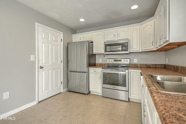 kitchen with white cabinets, sink, light tile patterned floors, and stainless steel appliances