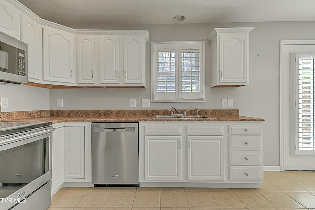 kitchen featuring stainless steel appliances, white cabinetry, a healthy amount of sunlight, and sink