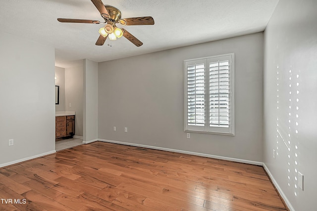 spare room featuring a textured ceiling, light hardwood / wood-style flooring, and ceiling fan