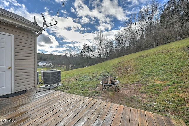 deck with central air condition unit, a lawn, and a fire pit