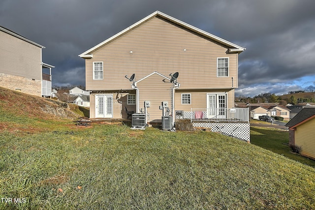 back of property featuring a lawn, central air condition unit, a wooden deck, and french doors