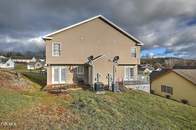 rear view of house with a yard, a deck, and central AC unit