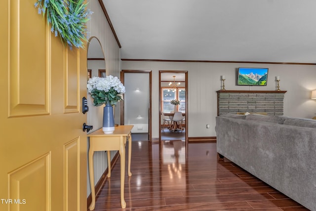 living room with dark wood-type flooring, a stone fireplace, and ornamental molding