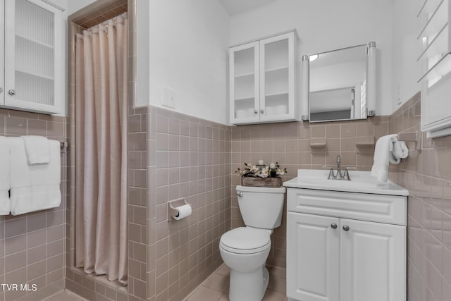 bathroom featuring tile patterned floors, walk in shower, vanity, tile walls, and toilet