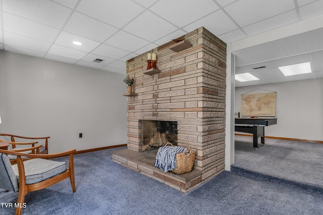 living room featuring carpet flooring, a stone fireplace, and a paneled ceiling