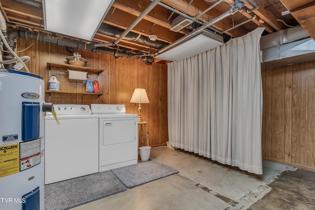 washroom with wood walls, washing machine and dryer, and water heater