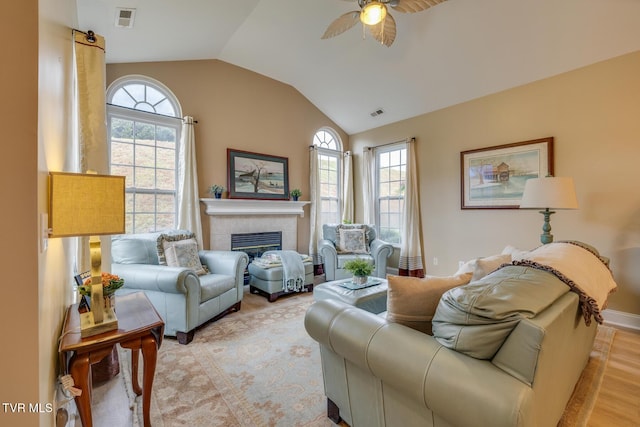 living room featuring ceiling fan, a fireplace, light hardwood / wood-style floors, and lofted ceiling