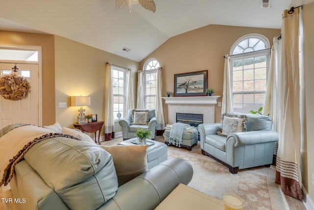 living room featuring a tile fireplace, a wealth of natural light, vaulted ceiling, and ceiling fan