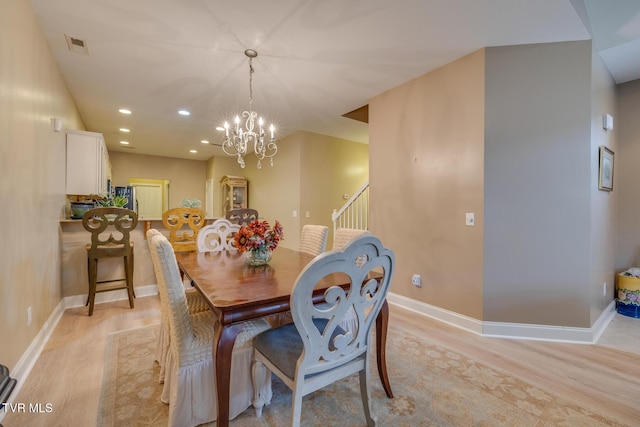 dining space featuring light wood-type flooring and a chandelier