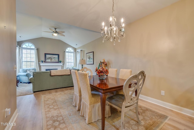 dining space with lofted ceiling, light hardwood / wood-style flooring, and ceiling fan with notable chandelier