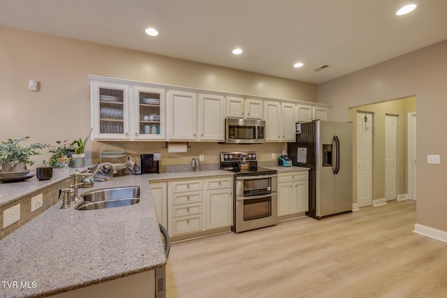 kitchen featuring light stone countertops, stainless steel appliances, light hardwood / wood-style flooring, and sink