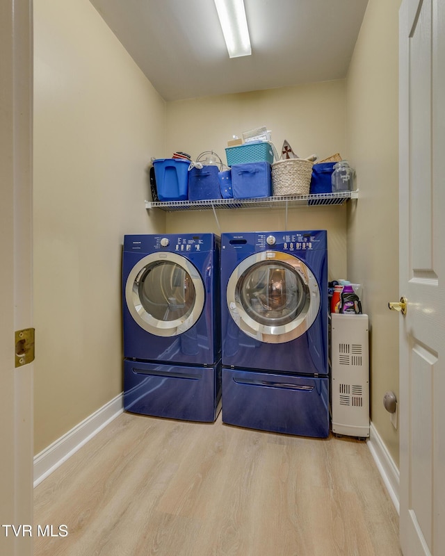 clothes washing area with washing machine and clothes dryer and light hardwood / wood-style floors