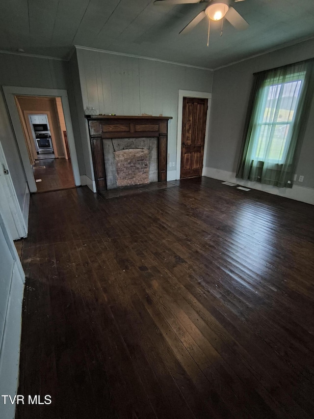 unfurnished living room featuring dark hardwood / wood-style floors, ceiling fan, and a fireplace