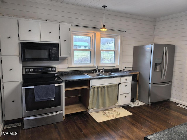 kitchen featuring wooden walls, sink, white cabinets, and appliances with stainless steel finishes