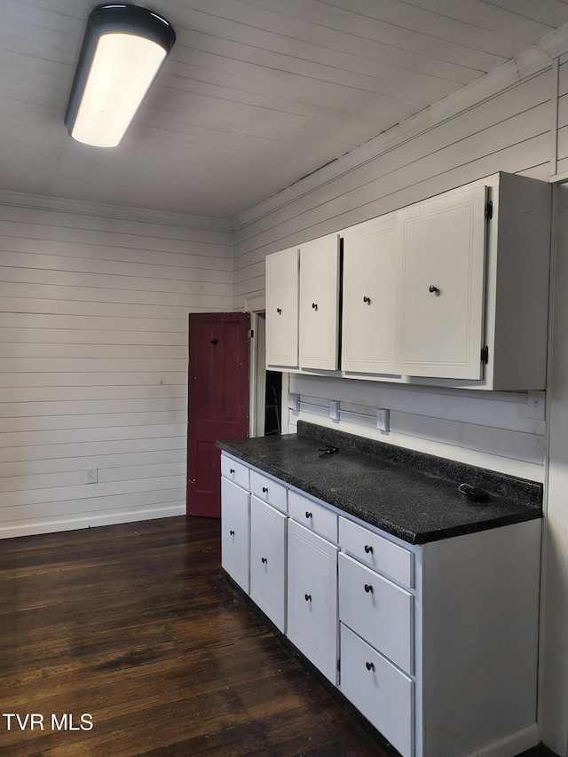 kitchen featuring white cabinetry, wooden walls, and dark hardwood / wood-style floors