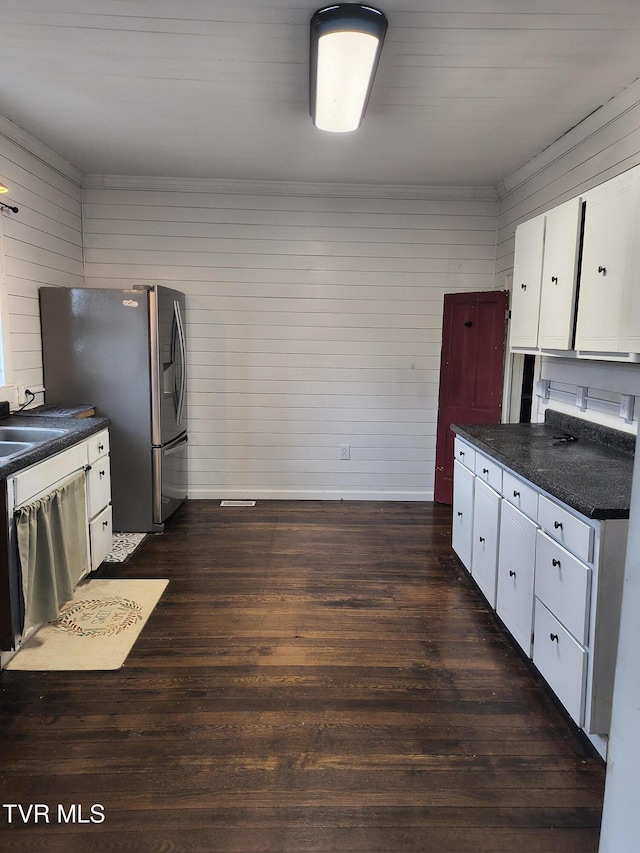 kitchen with white cabinets, stainless steel refrigerator with ice dispenser, dishwasher, and wood walls