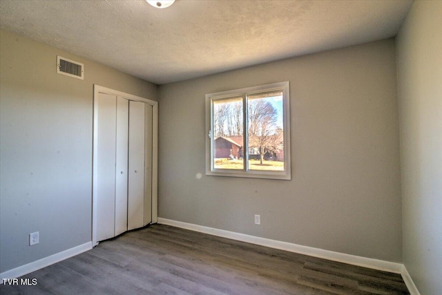 unfurnished bedroom featuring hardwood / wood-style flooring, a textured ceiling, and a closet