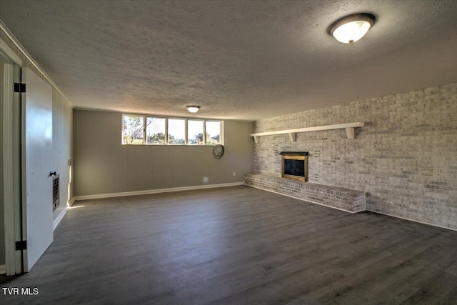 interior space with a textured ceiling, brick wall, dark hardwood / wood-style floors, and a brick fireplace