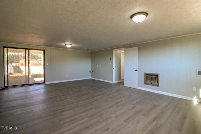 unfurnished room featuring heating unit, hardwood / wood-style floors, and a textured ceiling