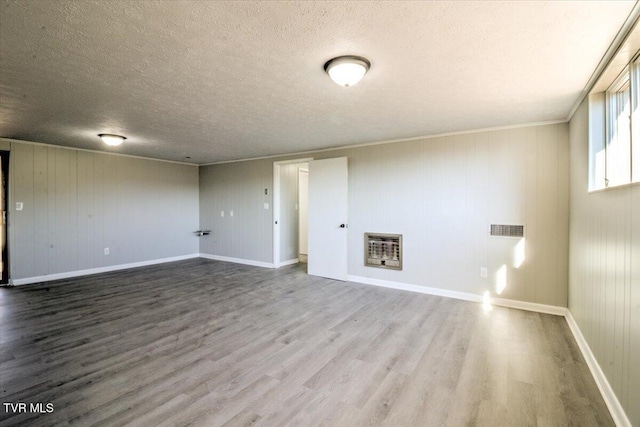 interior space featuring heating unit, crown molding, a textured ceiling, and hardwood / wood-style flooring