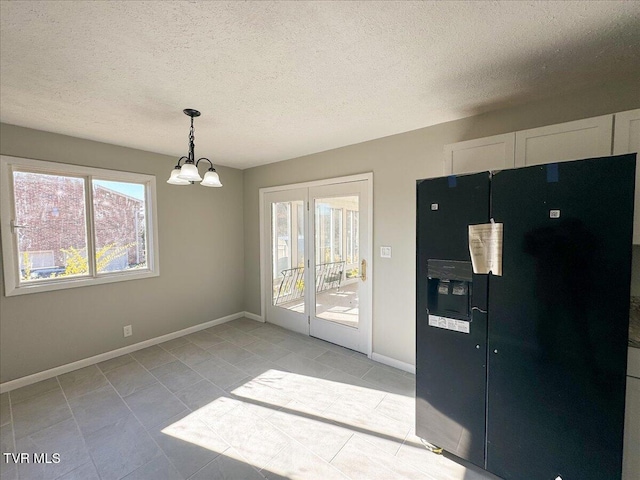 kitchen with white cabinetry, a chandelier, decorative light fixtures, black fridge with ice dispenser, and light tile patterned floors