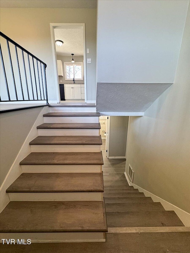 stairway featuring wood-type flooring and a textured ceiling