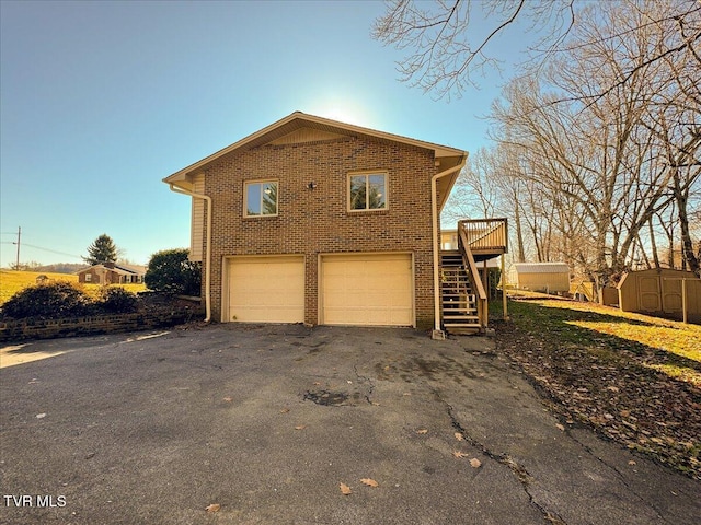 view of side of home with a garage, a wooden deck, and a storage shed