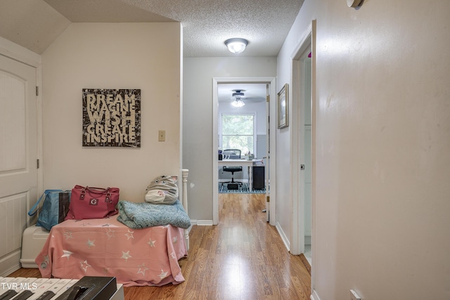 corridor with a textured ceiling and hardwood / wood-style flooring