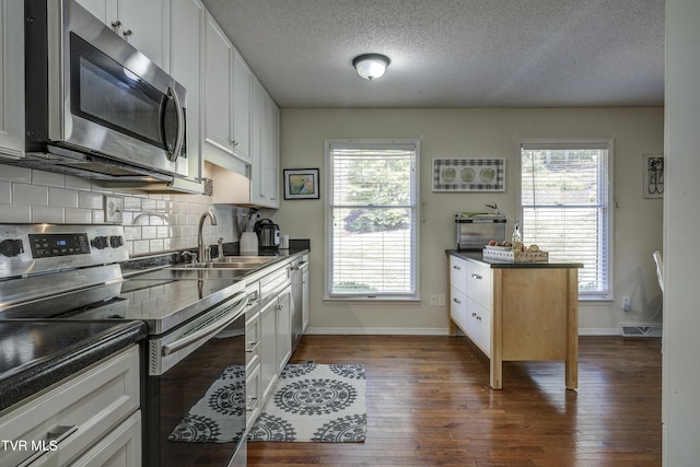 kitchen with white cabinetry, sink, appliances with stainless steel finishes, and dark wood-type flooring