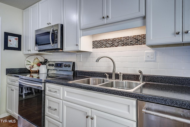 kitchen with dark wood-type flooring, sink, appliances with stainless steel finishes, tasteful backsplash, and white cabinetry