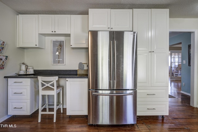 kitchen with stainless steel fridge, a textured ceiling, white cabinetry, and dark wood-type flooring