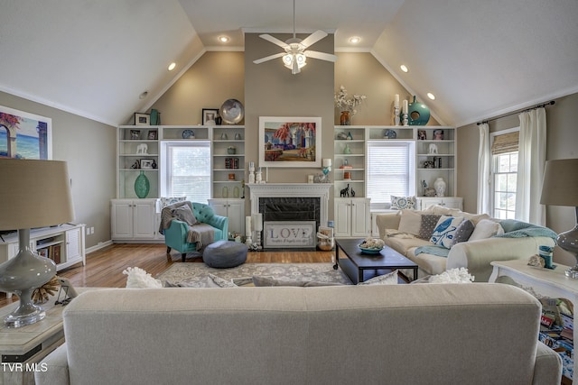 living room featuring ceiling fan, light hardwood / wood-style flooring, a high end fireplace, and ornamental molding