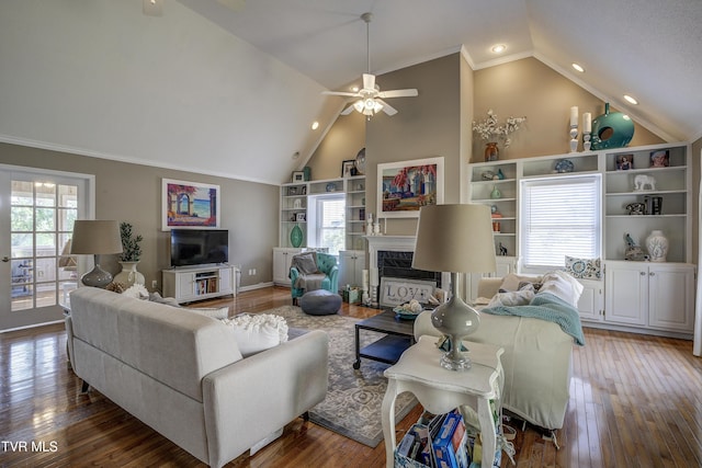 living room featuring ceiling fan, crown molding, hardwood / wood-style floors, vaulted ceiling, and a fireplace