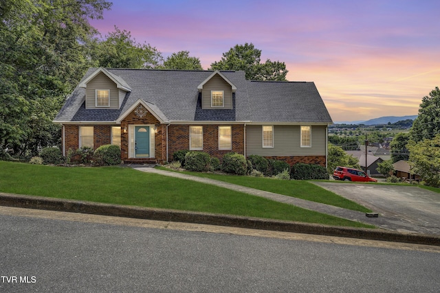 cape cod house featuring a lawn