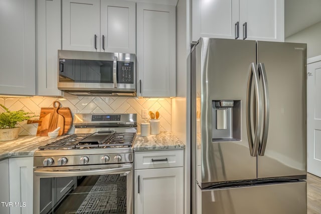 kitchen with light stone counters, white cabinetry, appliances with stainless steel finishes, and tasteful backsplash