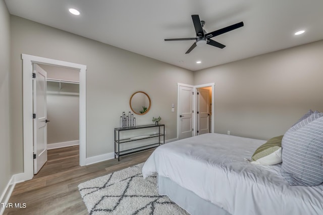 bedroom with a walk in closet, ceiling fan, a closet, and hardwood / wood-style floors