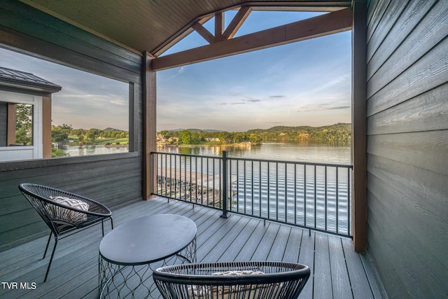 deck at dusk featuring a water view