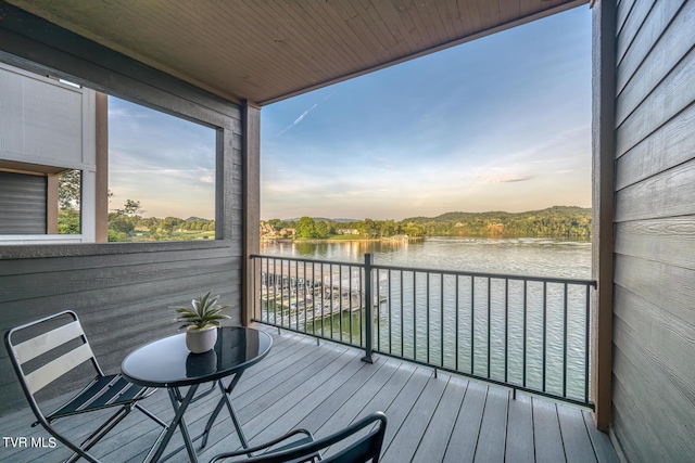 deck at dusk featuring a water view