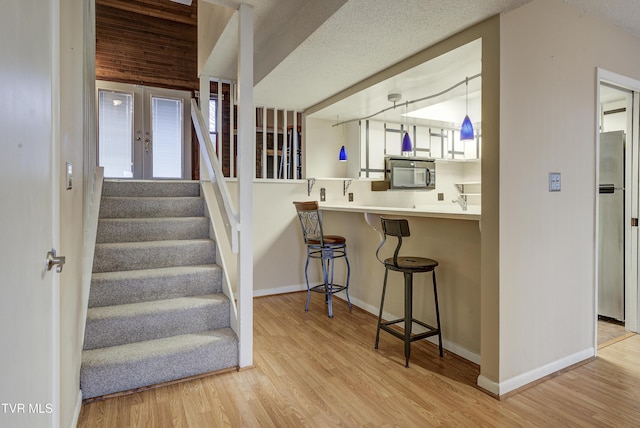 stairway featuring french doors, wood-type flooring, and a textured ceiling