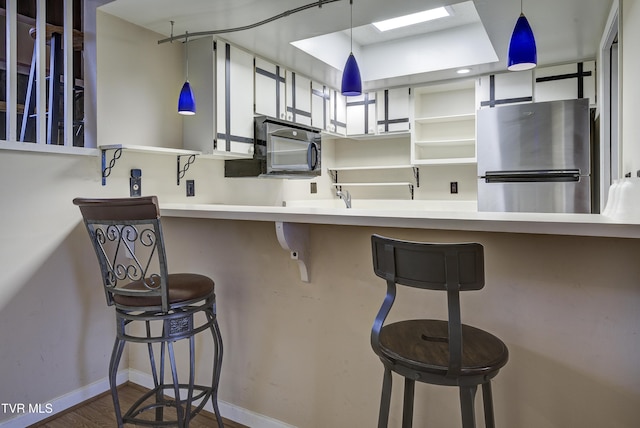 kitchen featuring a kitchen breakfast bar, stainless steel fridge, kitchen peninsula, and decorative light fixtures