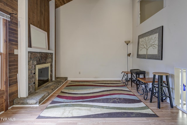 living room featuring a stone fireplace, light wood-type flooring, and high vaulted ceiling