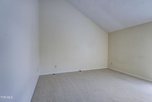 carpeted empty room featuring vaulted ceiling