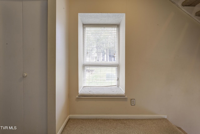 carpeted empty room with a textured ceiling and plenty of natural light