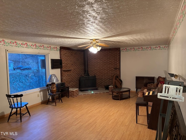 living room with a wood stove, ceiling fan, a textured ceiling, and hardwood / wood-style flooring