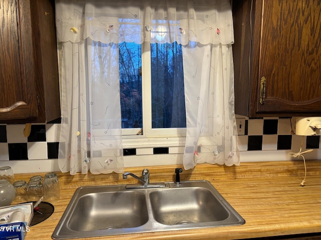 kitchen with decorative backsplash, dark brown cabinetry, and sink